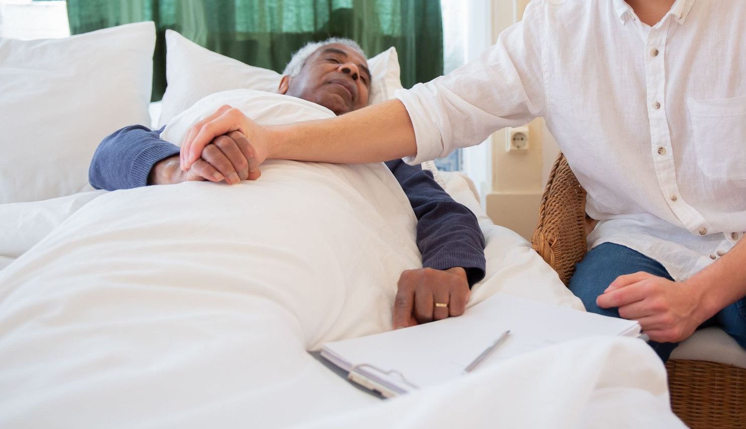 A young man comforts an elderly man in bed, foster warmth and care.