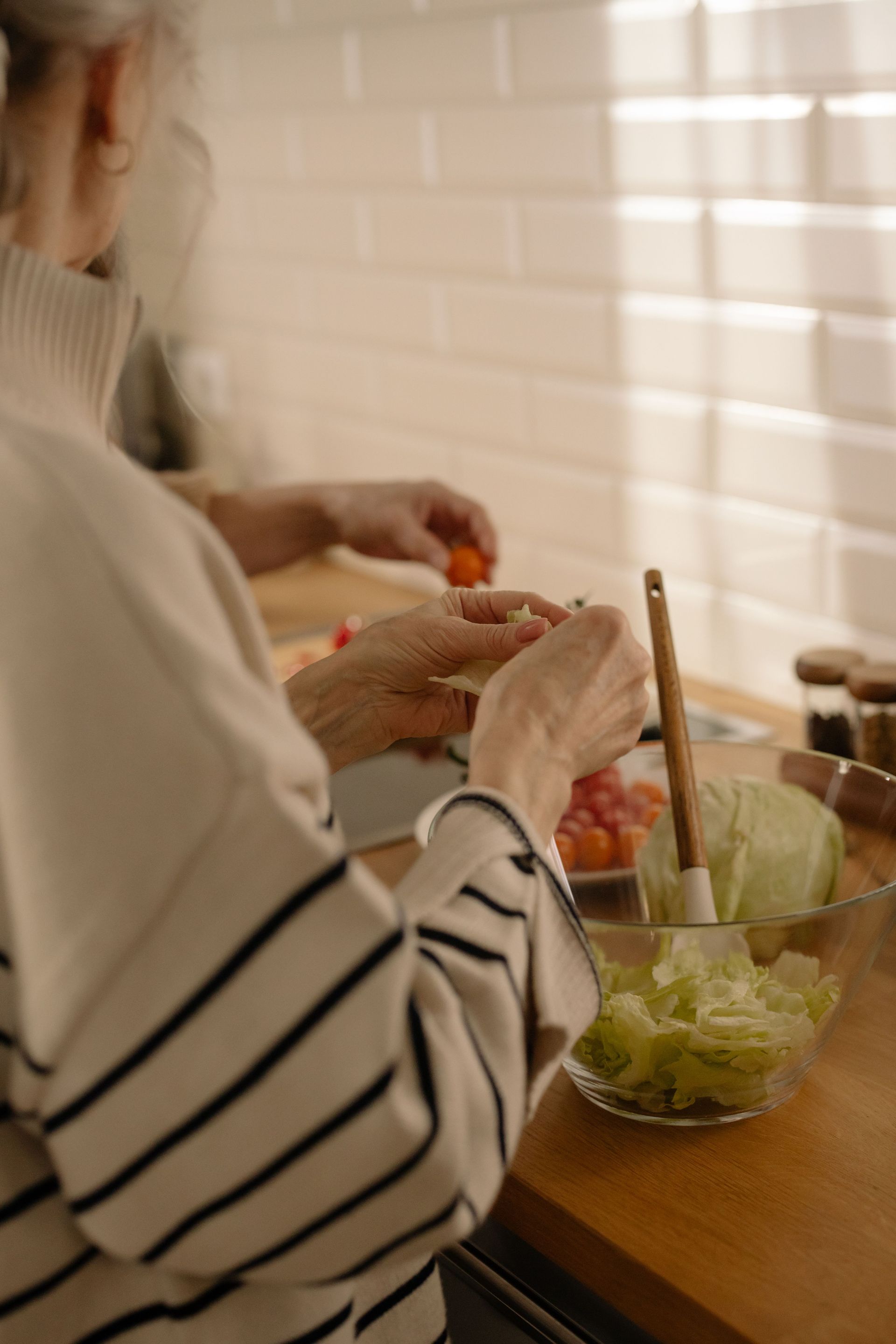 Senior woman preparing a fresh salad in a bright kitchen, showcasing healthy living and modern lifestyle.